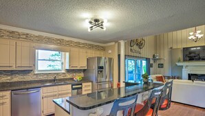Een moderne keuken met een centraal kookeiland, roestvrijstalen apparatuur en een eethoek met barstoelen.