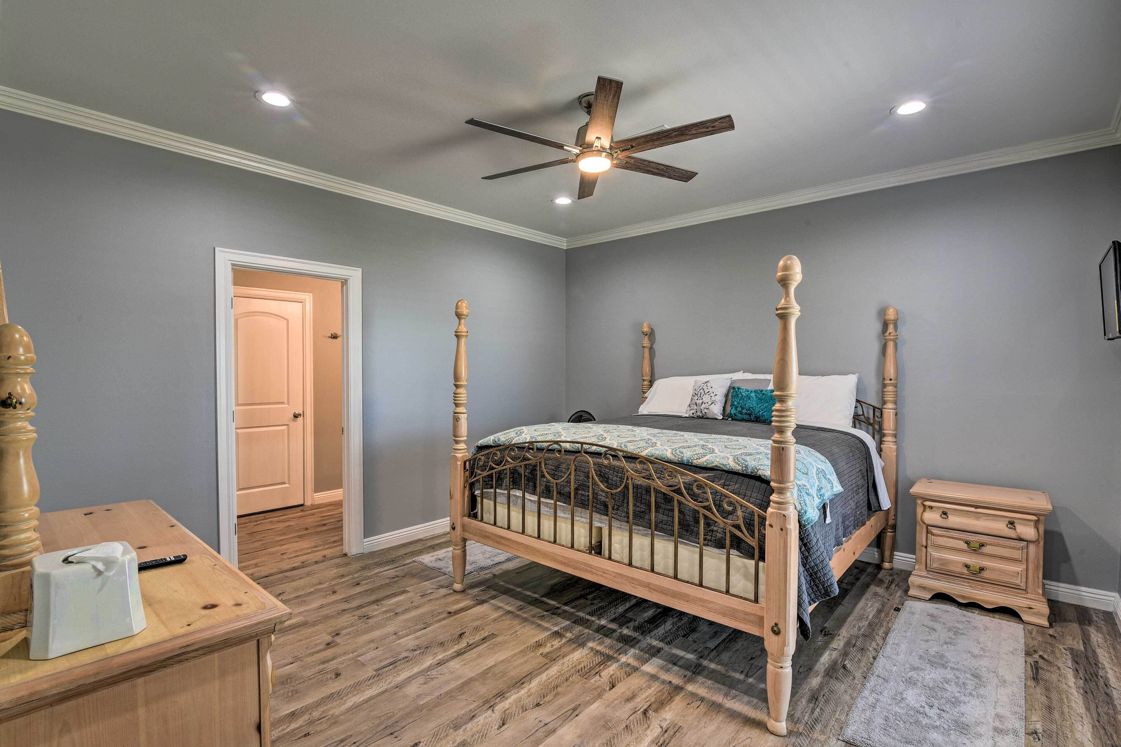 A bedroom with a four-poster bed, wooden nightstand, and a desk with a chair.