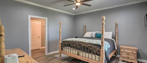 A bedroom with a four-poster bed, wooden nightstand, and a desk with a chair.