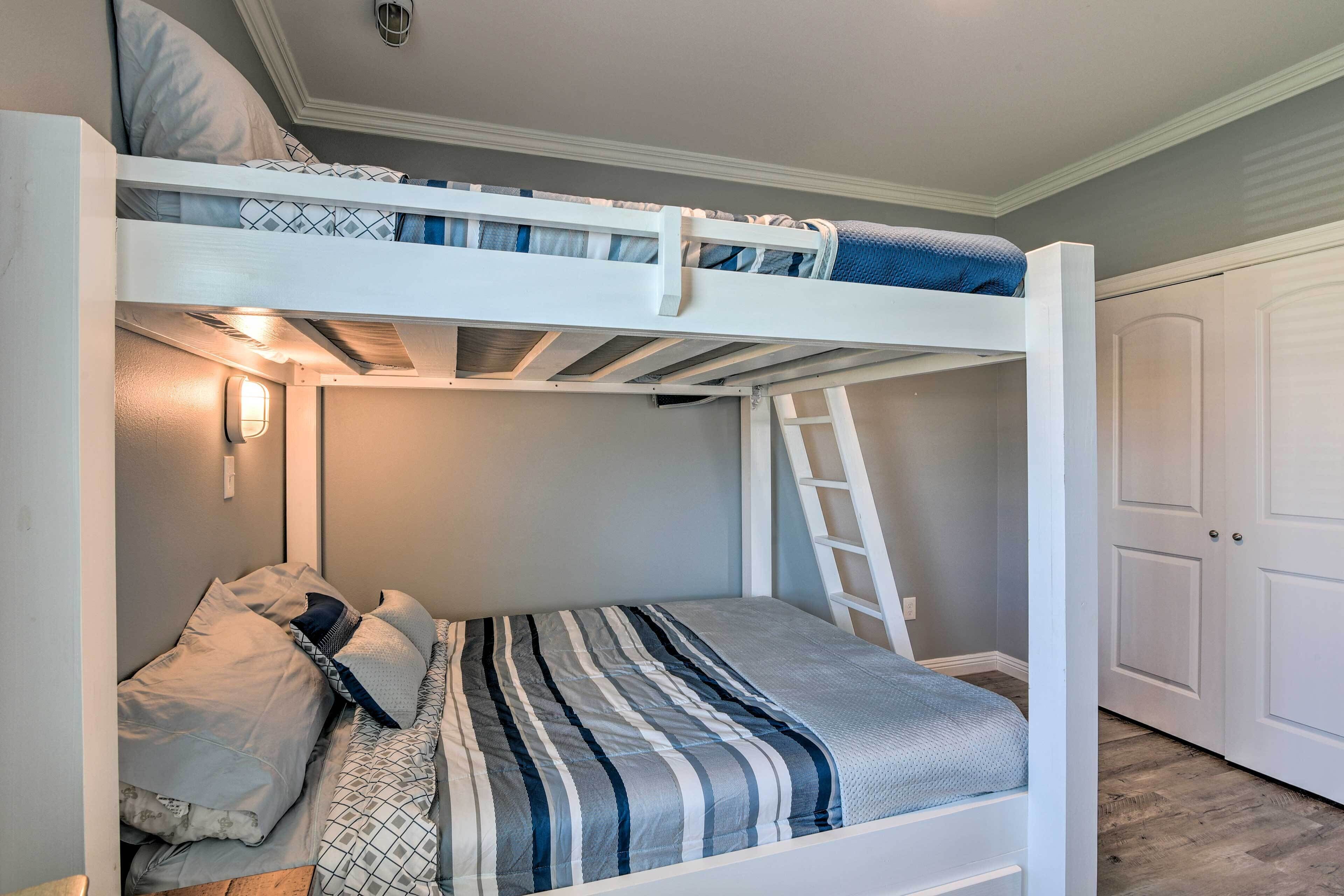 A bunk bed with a ladder, a bedside table, and a wall-mounted light fixture.