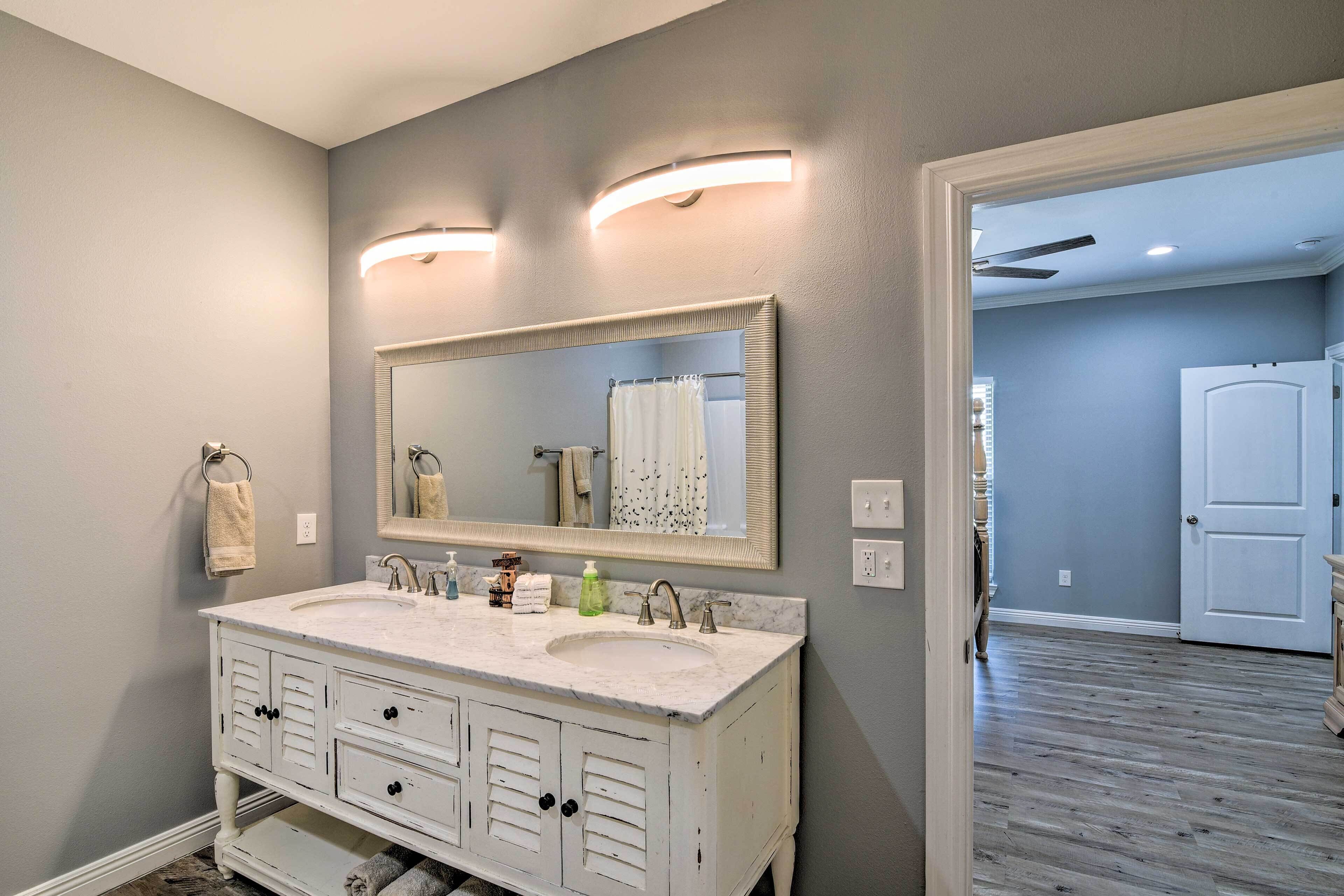 A bathroom with a white vanity, two sinks, a large mirror, and a shower curtain.