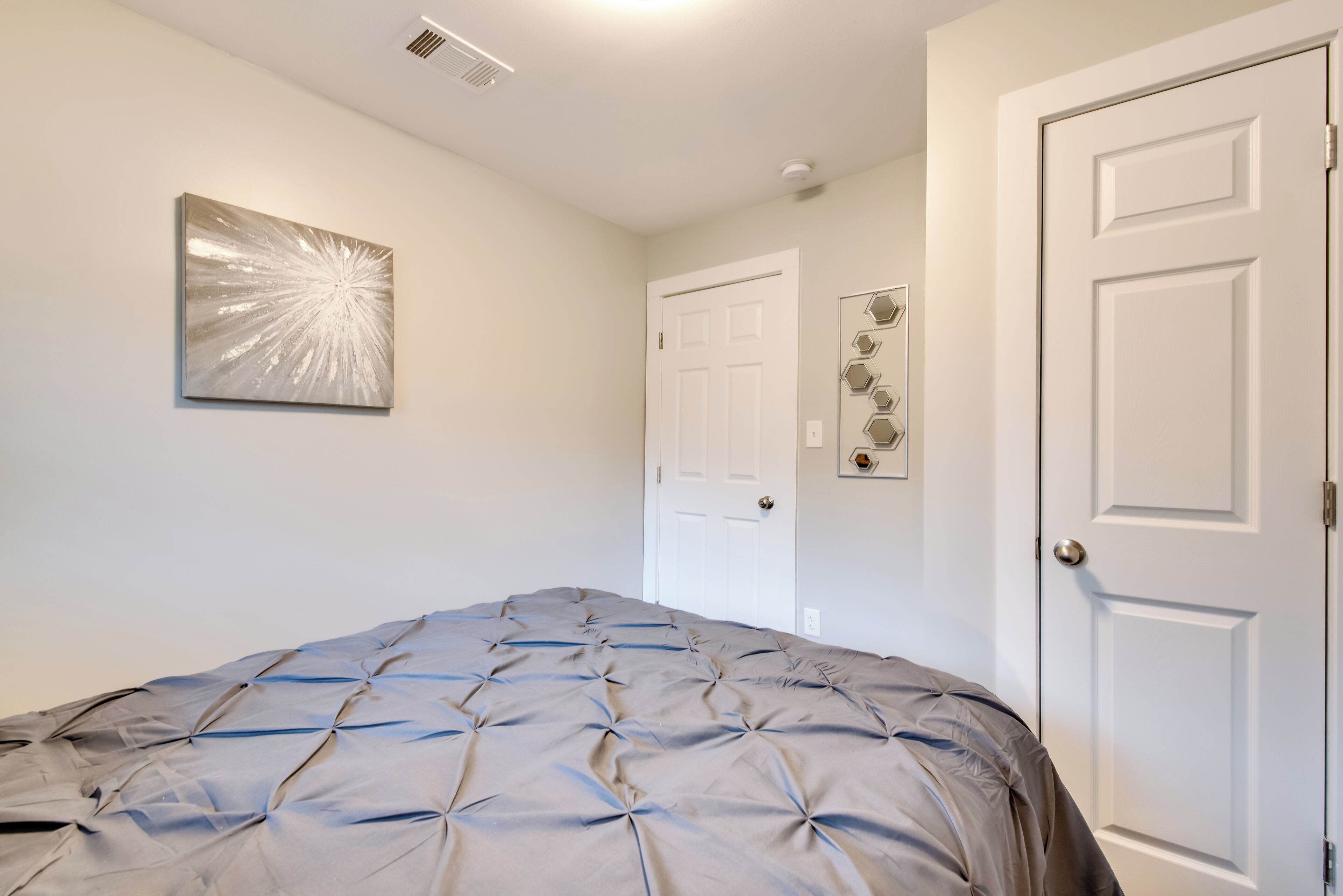 Un dormitorio con cama, una puerta y una obra de arte colgada en la pared.