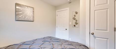 Un dormitorio con cama, una puerta y una obra de arte colgada en la pared.