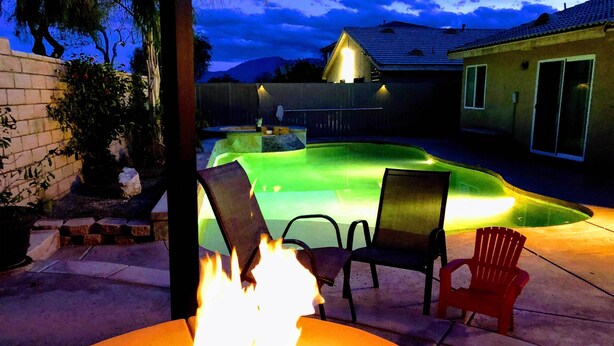 A backyard with a swimming pool, a fire pit, and outdoor furniture.