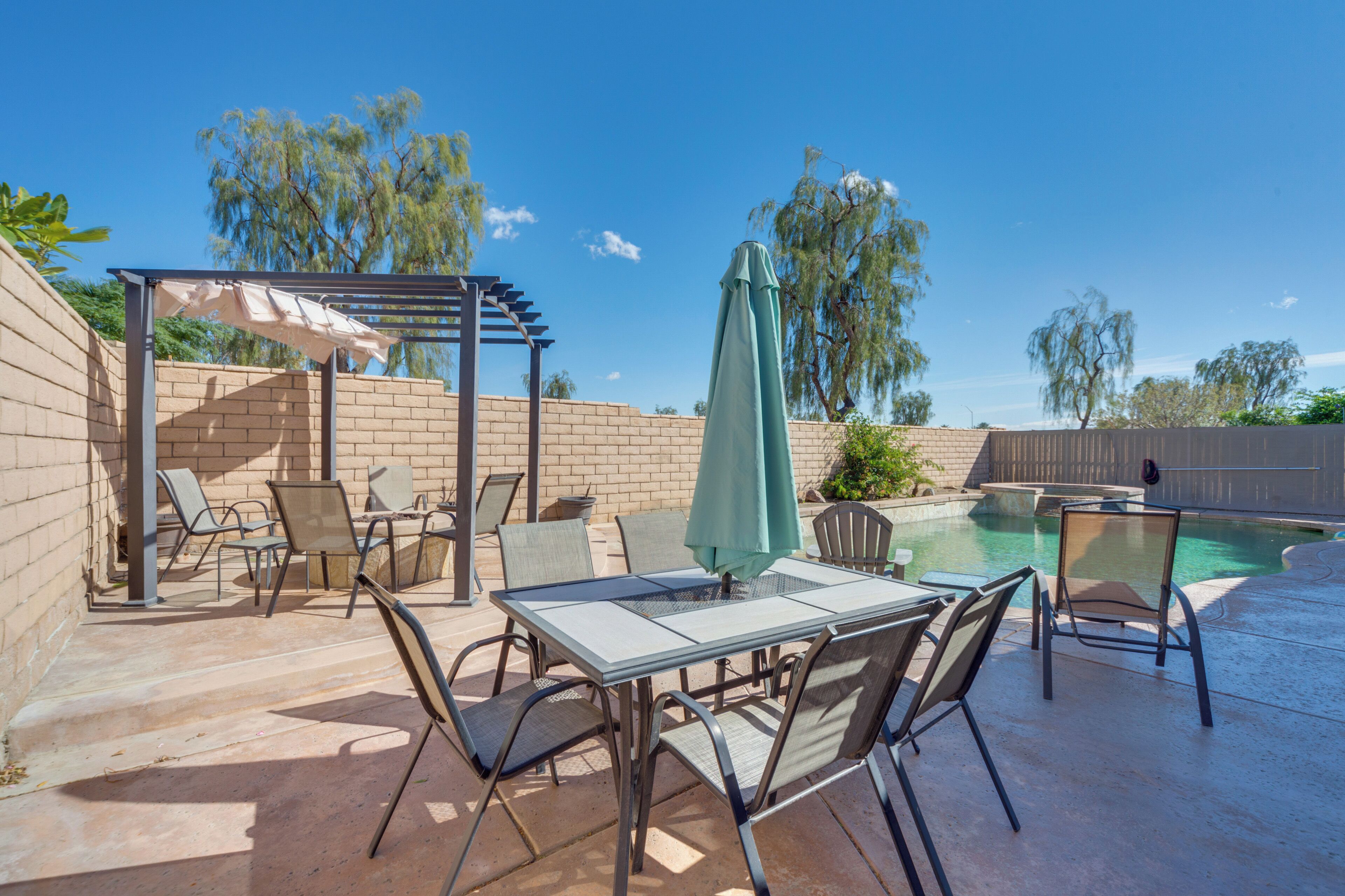 Eine Terrass mit Pool, Gartenmöbeln und einer Pergola.