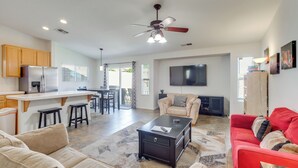 A spacious living area with a kitchen, dining area, and a red sofa.