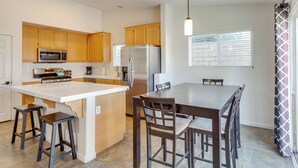 A modern kitchen with wooden cabinets, stainless steel appliances, and a central island with bar stools.