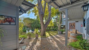 A covered patio area with a brick floor, potted plants, and a wooden barrel. - Luxurious Downtown Lodi Apartment in Wine Country! (Lodi)