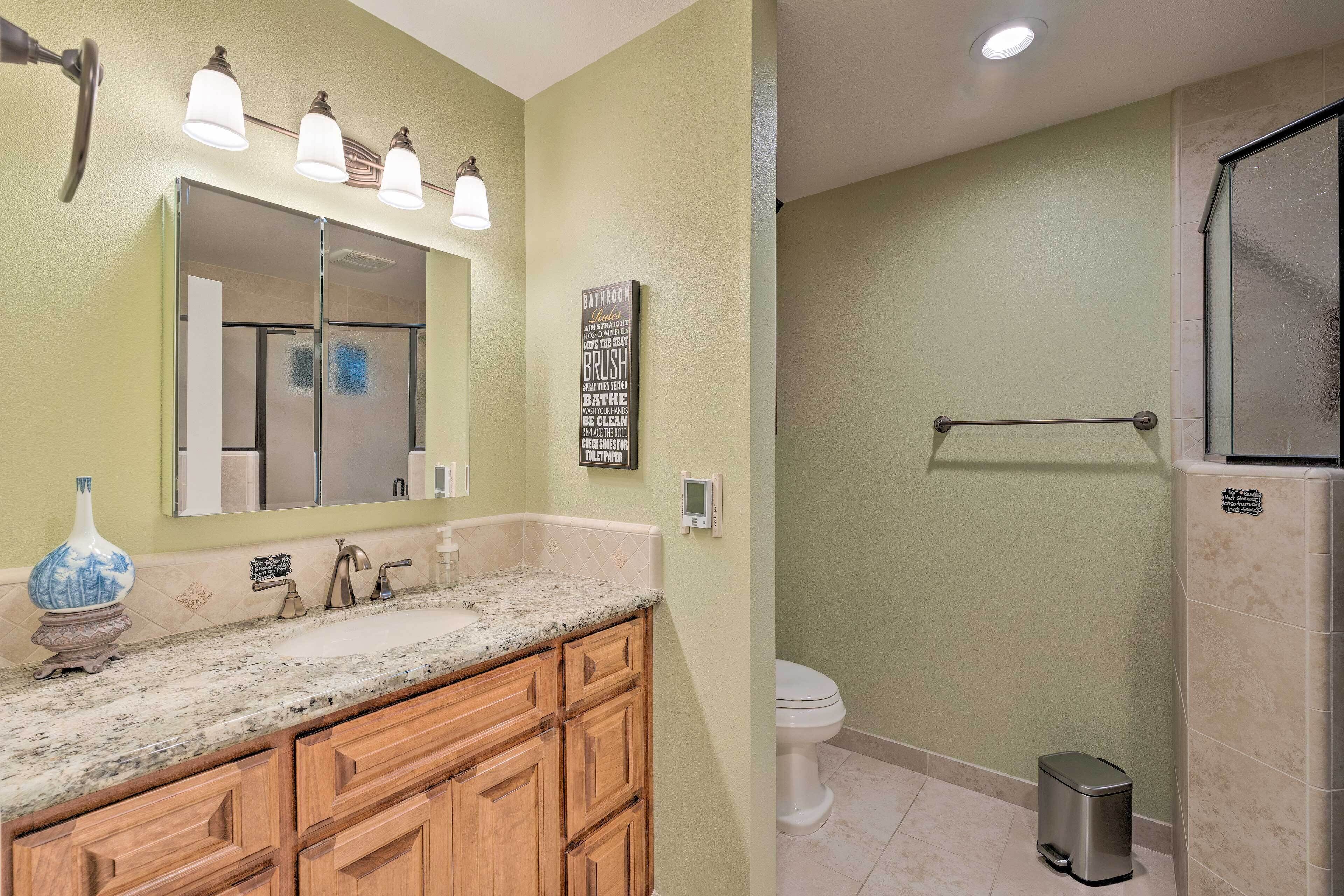 A bathroom with a sink, mirror, vanity, and a toilet.