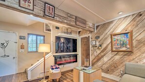 A cozy interior with a wooden wall, a television, a sofa, and a small table. - Luxurious Downtown Lodi Apartment in Wine Country! (Lodi)