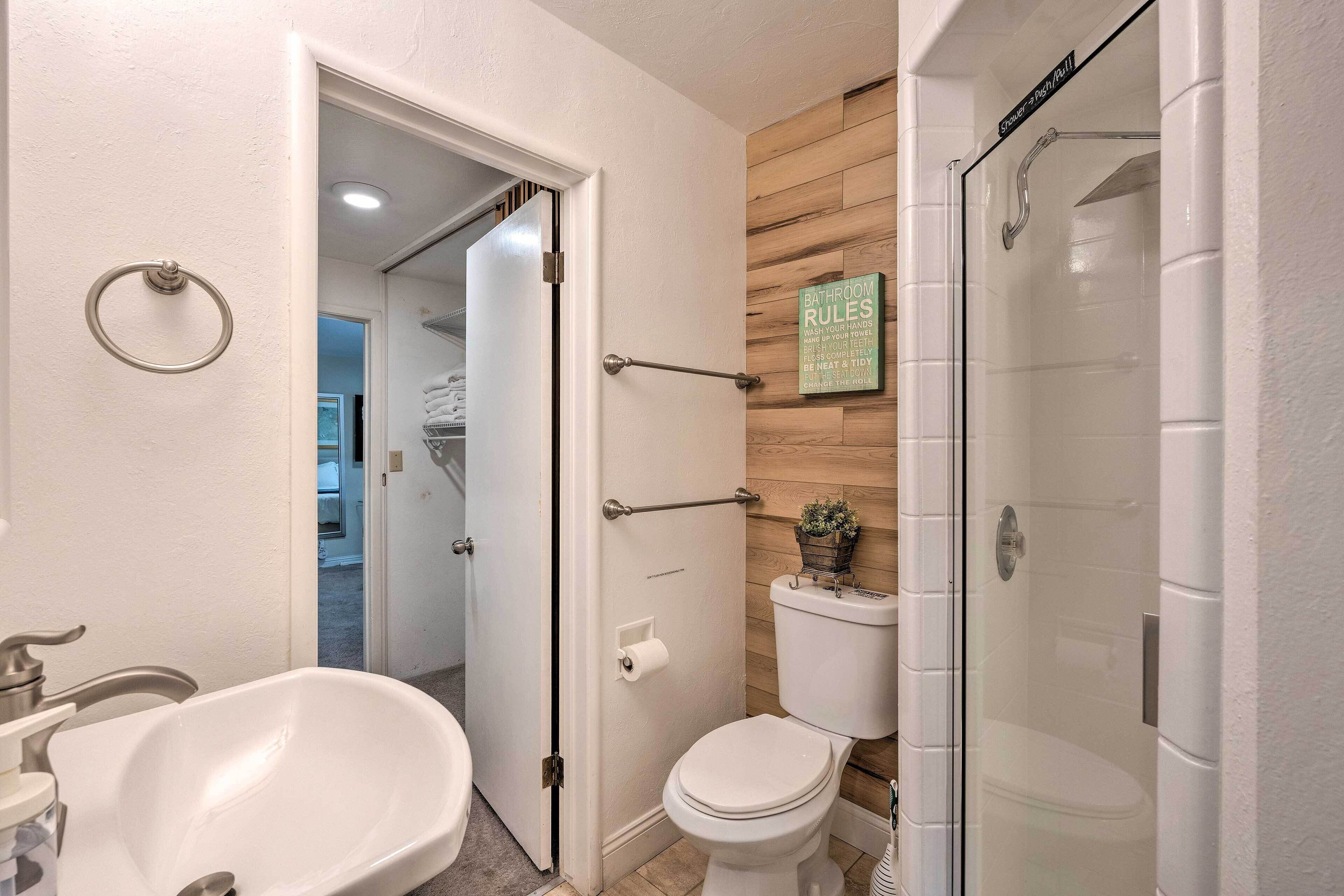 Un baño con bañera, inodoro y ducha con mampara de vidrio.