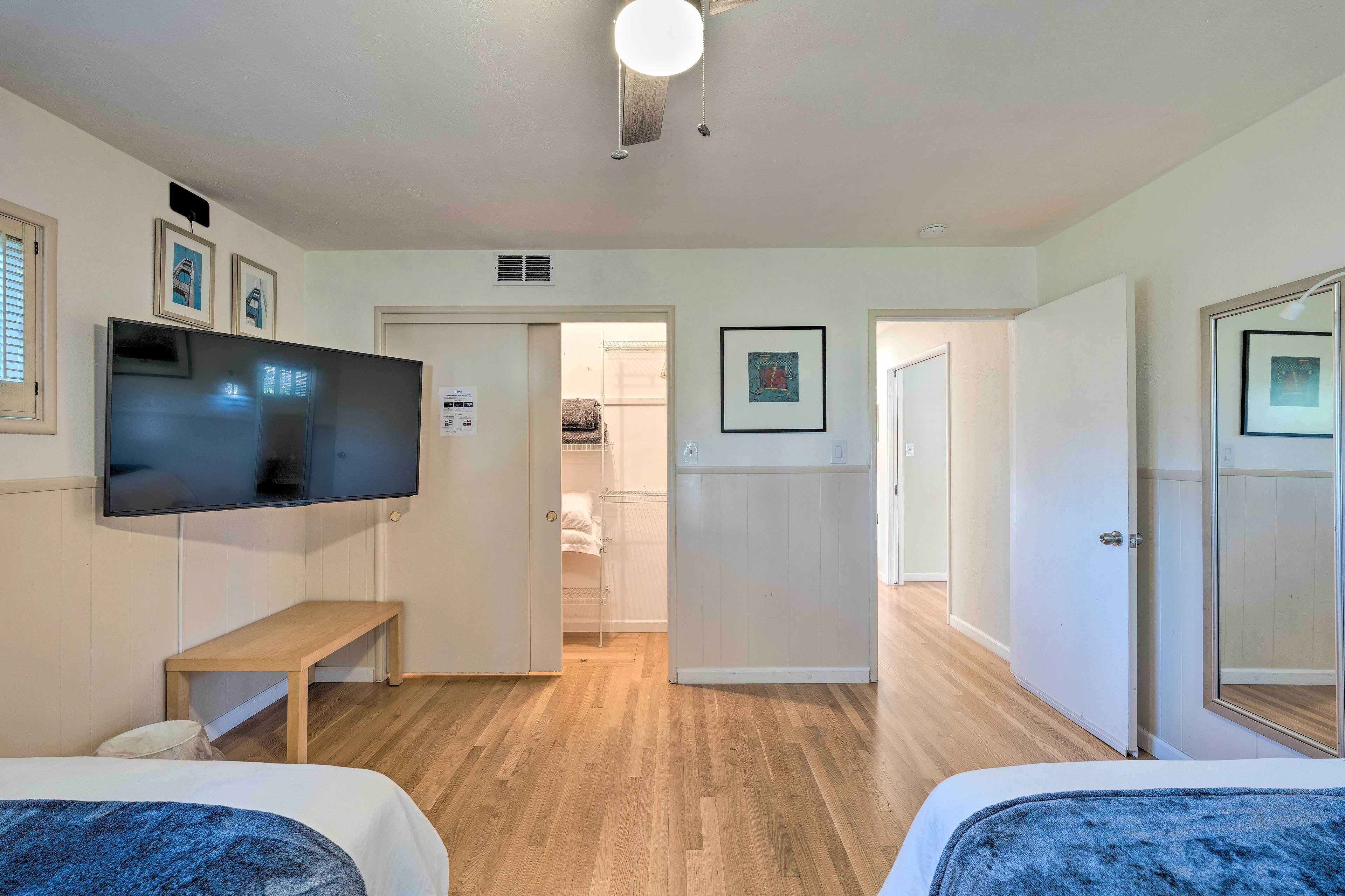 Une chambre d’hôtel avec deux lits, un téléviseur à écran plat, un banc et une porte donnant sur une salle de bain.