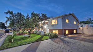 A two-story house with a garage, a well-maintained lawn, and a driveway leading to the front door. - Private Yard + Patio: Denver Area Home! (Northglenn)