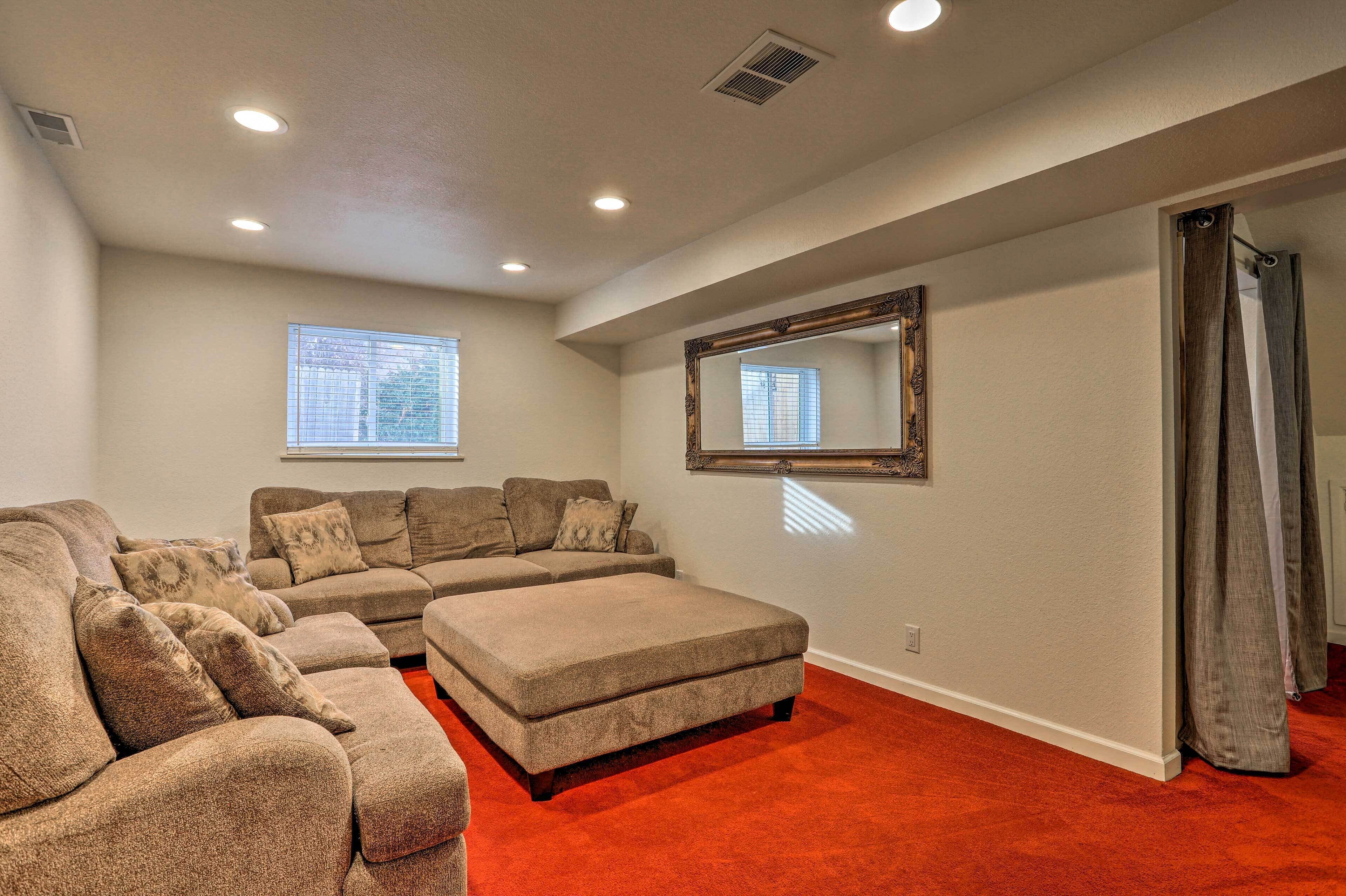 A spacious living room with a sectional sofa, a large mirror, and a red carpet.
