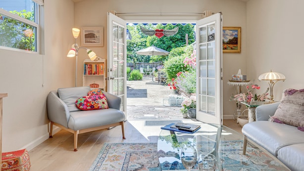 A cozy living room with a glass coffee table, a grey sofa, and a comfortable armchair. - Romantic Casita w/ Garden + Deck 2 Miles to Plaza! (Sonoma)