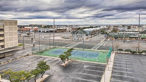 Ein Parkplatz mit Tennisplatz, Gebäuden und bewölktem Himmel.
