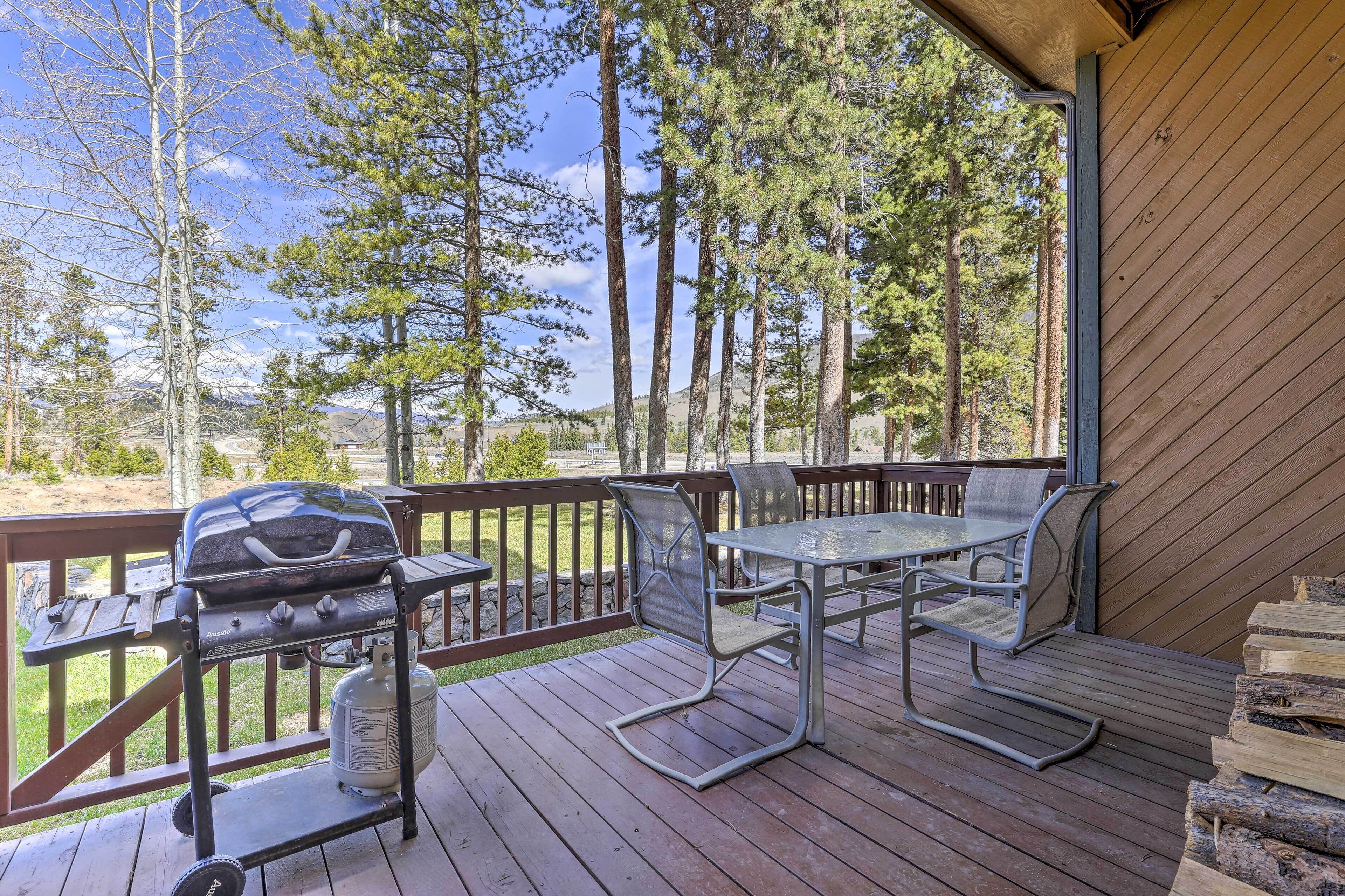 Eine Terrassenausstattung mit Grill, Metallstühlen und Tisch.