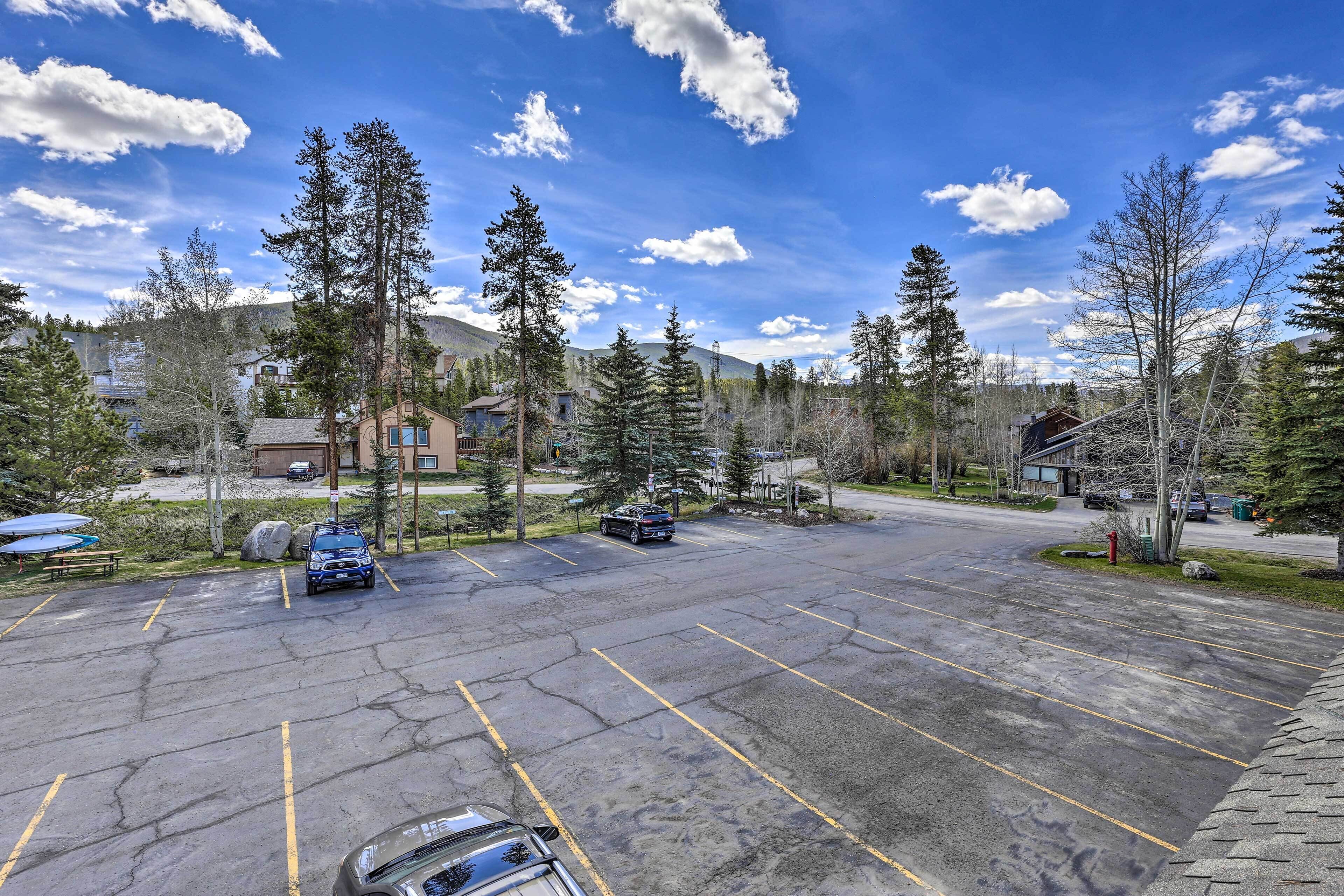 A parking lot with several cars, surrounded by trees and buildings.