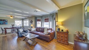 A spacious living room with a brown leather sofa, a dining table, and a wooden cabinet. - Tulsa Home w/ Yard: 5 Mi to Downtown! (Tulsa)