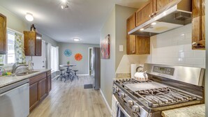 A modern kitchen with wooden cabinets, a stainless steel stove, and a tiled backsplash. - Tulsa Home w/ Yard: 5 Mi to Downtown! (Tulsa)