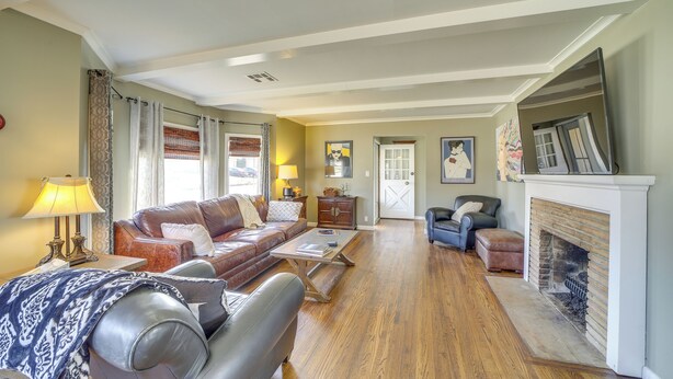 A spacious living room with a fireplace, leather sofas, and hardwood flooring. - Tulsa Home w/ Yard: 5 Mi to Downtown! (Tulsa)