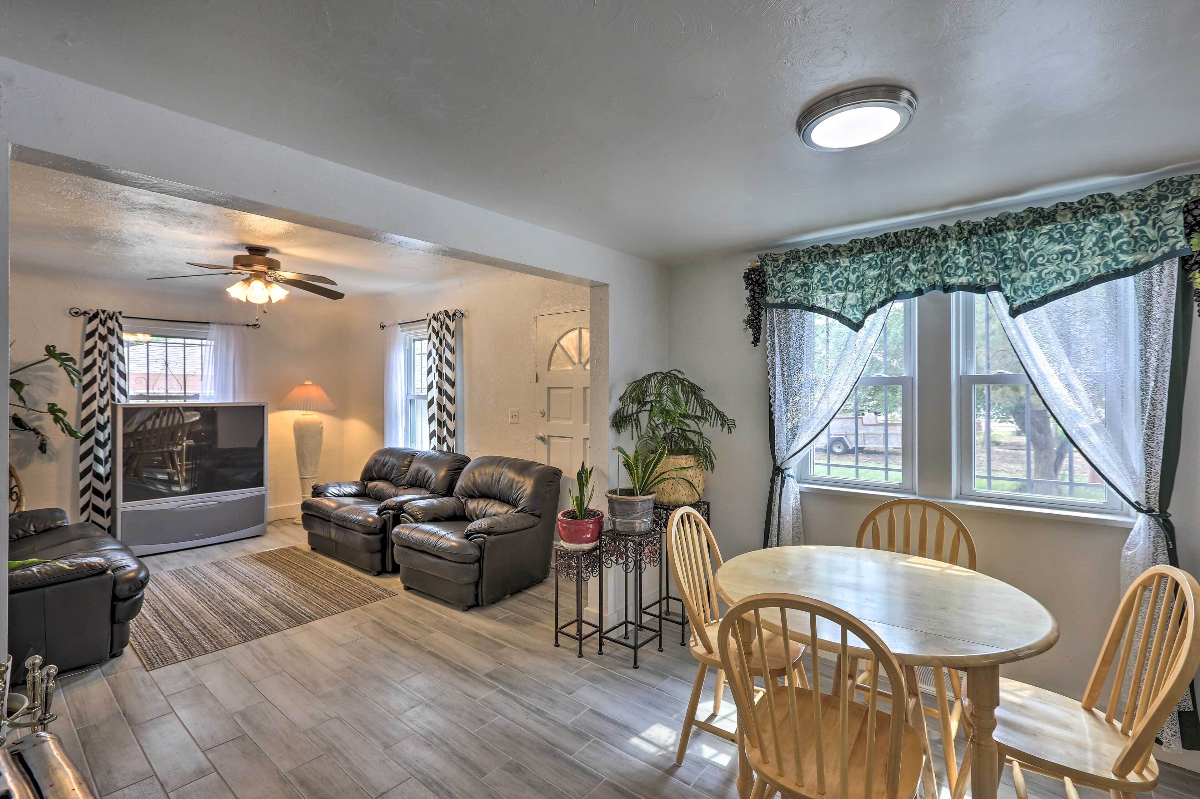 A living room with a sofa, a TV, a ceiling fan, and a dining area with a table and chairs.