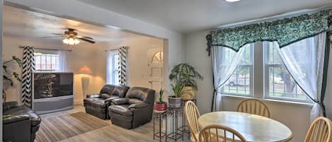A living room with a sofa, a TV, a ceiling fan, and a dining area with a table and chairs.