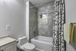 A bathroom with a toilet, bathtub, and shower curtain.