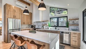 A modern kitchen with wooden cabinets, stainless steel appliances, and a large island with bar stools.