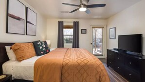 A hotel room with a bed, a television, a ceiling fan, and a door with a view. - Cottonwoods 419 (Moab)