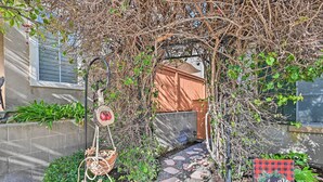 A garden pathway leading to a wooden gate with a 'Welcome' sign, surrounded by greenery and a stone-tiled path. - Chula Vista Studio w/ Hot Tub ~ 9 Mi to Downtown (Chula Vista)