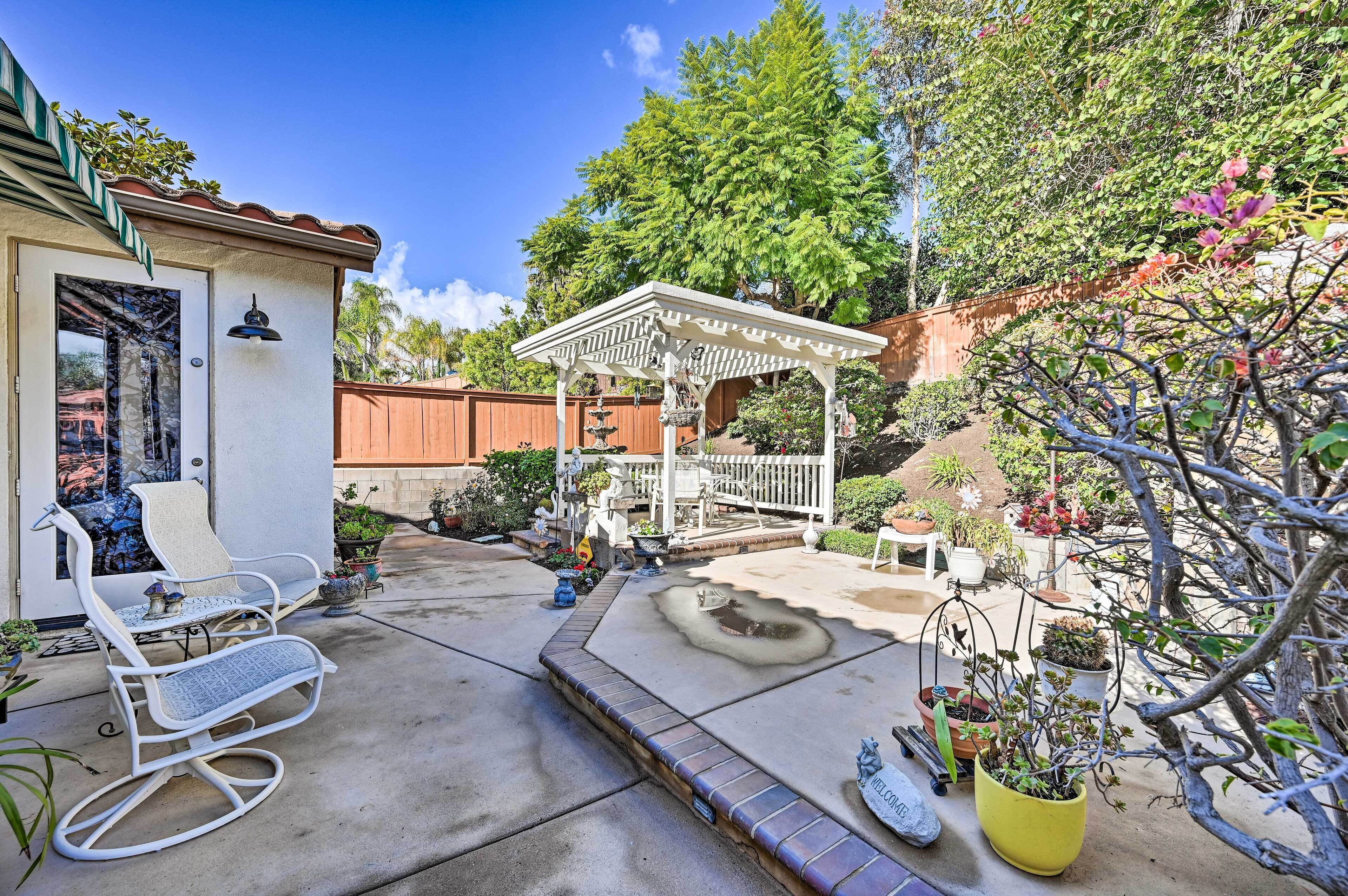 Eine Terrasse mit Pergola, Sitzgelegenheiten im Freien und Topfpflanzen.
