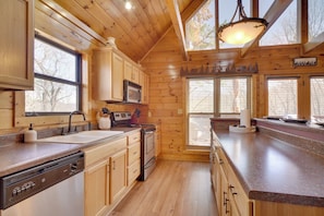Une cuisine avec des meubles de rangement en bois, un four à micro-ondes, une cuisinière et un lave-vaisselle.
