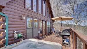 Une terrasse en bois avec un jacuzzi, un barbecue extérieur et du mobilier de jardin.