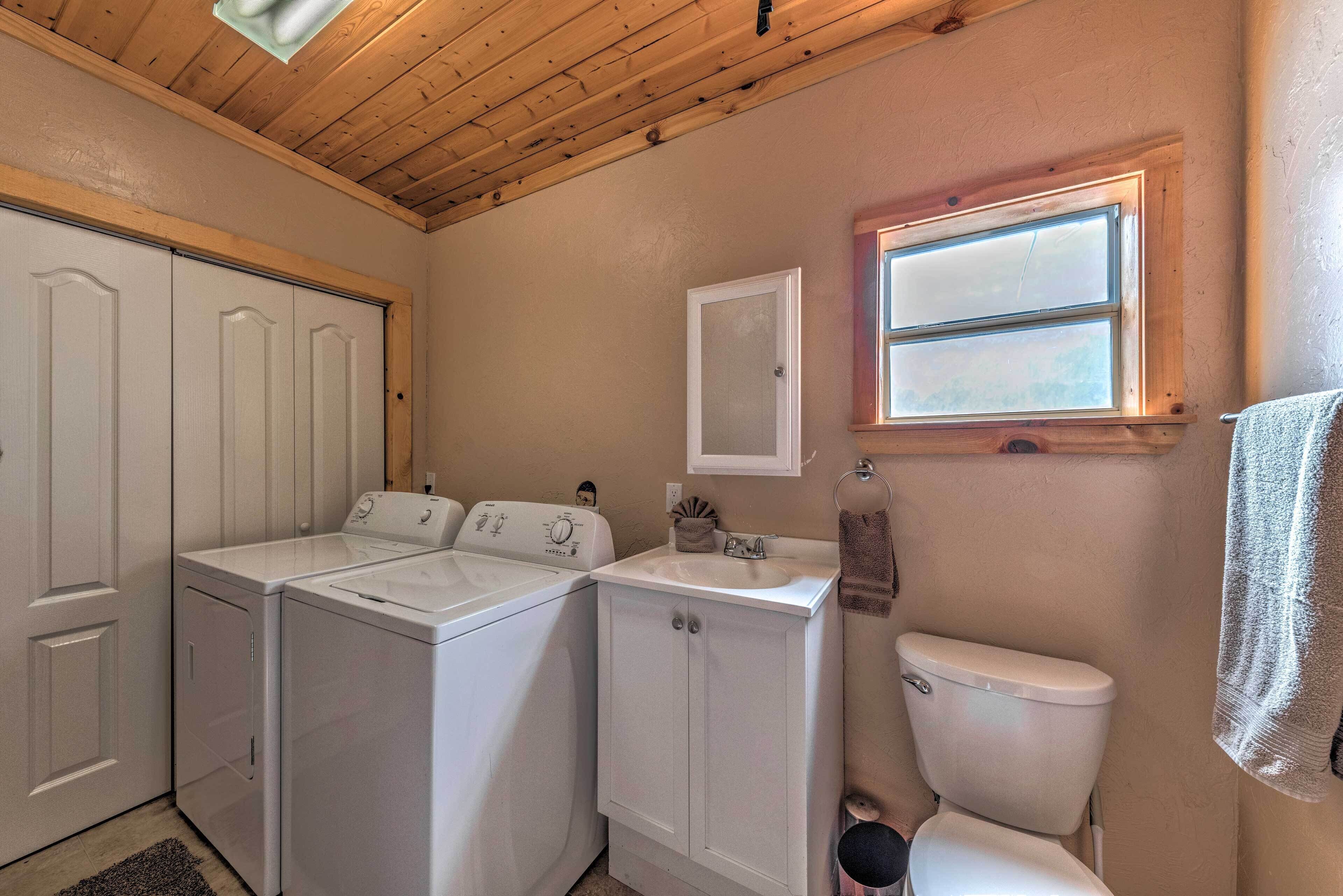 A laundry room with two washing machines, a sink, and a toilet.