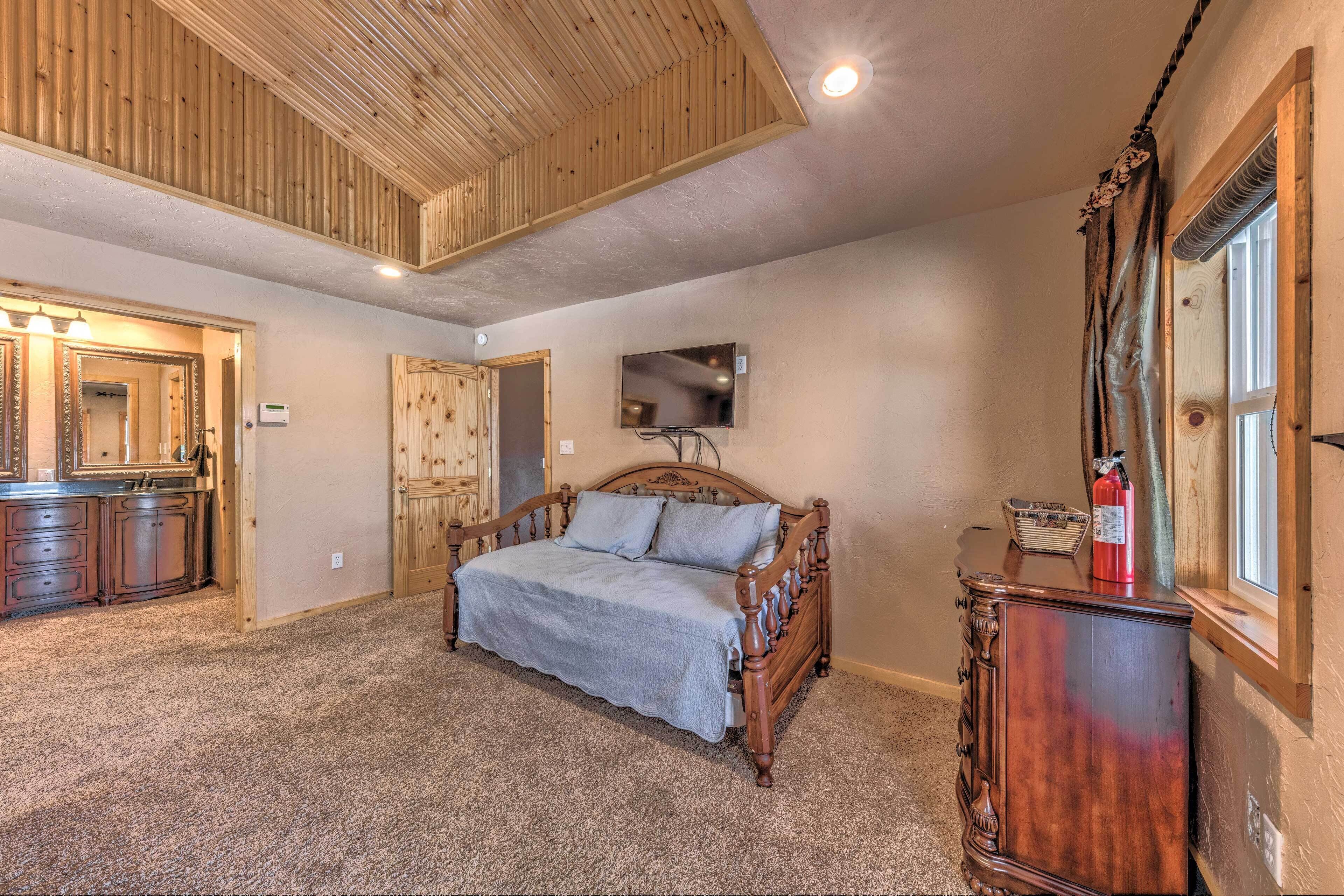 Een slaapkamer met een houten bed, een kapstok, een spiegel en een televisie aan de muur.