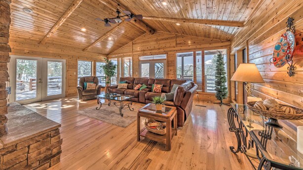 Un salón espacioso con techo de madera, ventanas amplias, chimenea y una zona de estar acogedora.