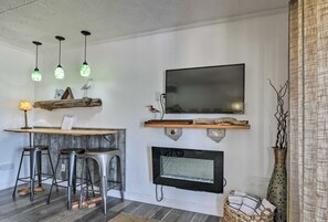 A modern living room with a flat-screen TV, a fireplace, and three hanging pendant lights.