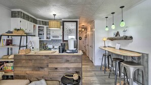 A modern kitchen with wooden accents, a bar area with stools, and pendant lighting. - Steps to Sand + 2 Pools! Galveston Coastal Getaway (Galveston)