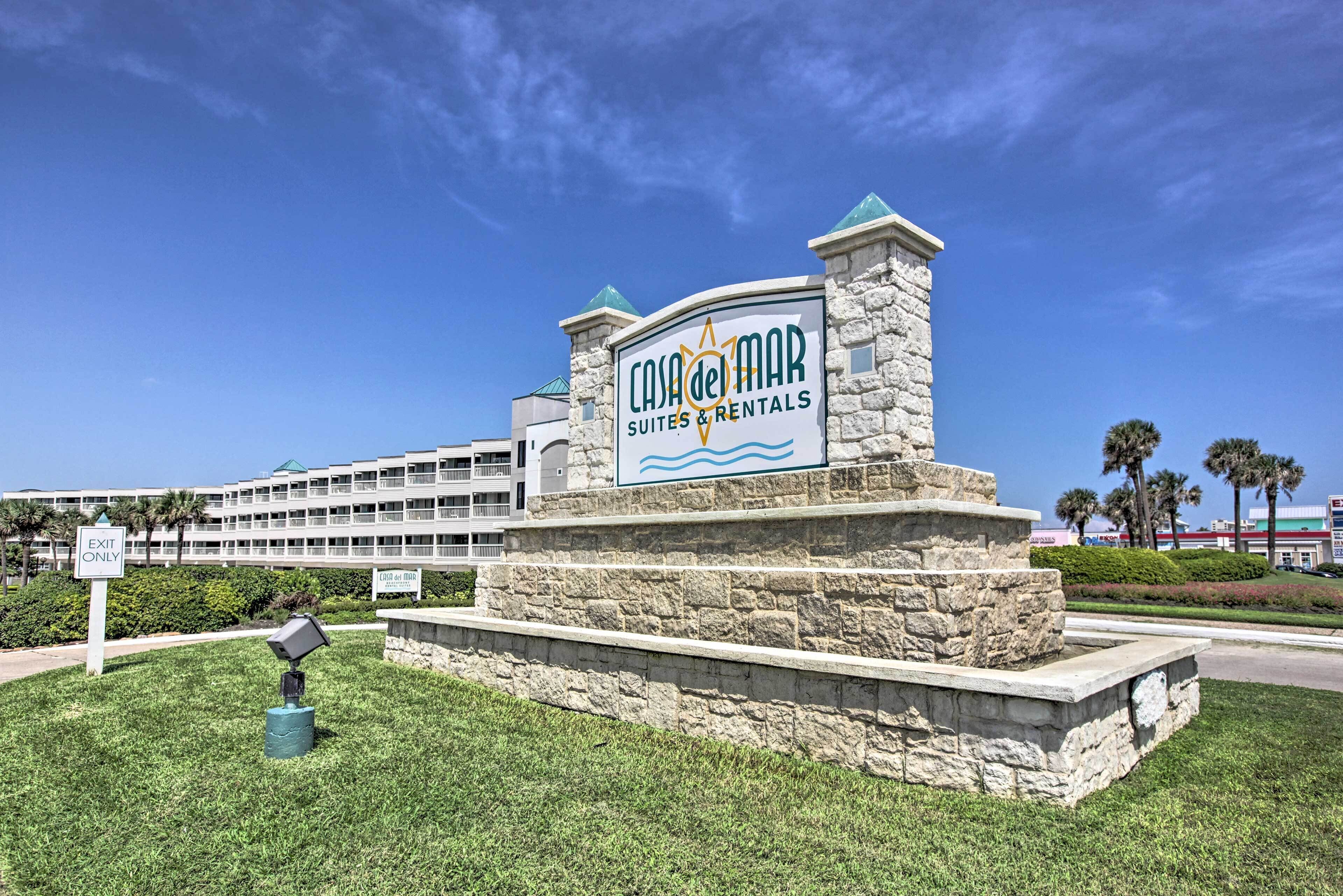A sign for Casa del Mar Suites & Rentals with a stone base and a clear blue sky in the background.