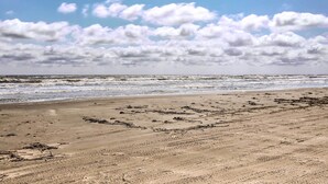A beach with a sandy shore and waves. - Steps to Sand + 2 Pools! Galveston Coastal Getaway (Galveston)