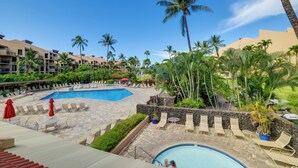 Zwembadgedeelte van een resort met meerdere zwembaden, ligbedden en palmbomen.