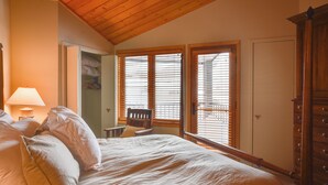 A bedroom with a wooden ceiling, a bed with white bedding, a nightstand with a lamp, and a wardrobe. - 'eagle's Nest' Crested Butte Townhome w/ Mtn Views (Crested Butte)