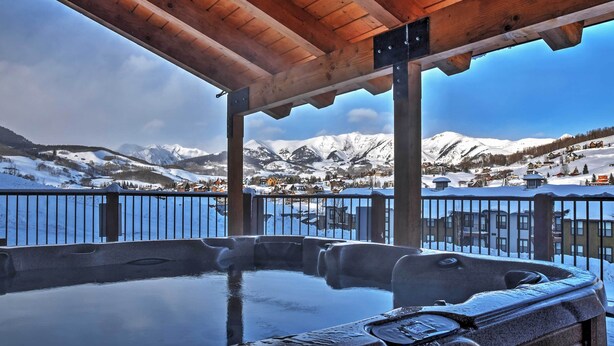 A hot tub under a wooden pergola with a view of snow-covered mountains and a lake. - 'eagle's Nest' Crested Butte Townhome w/ Mtn Views (Crested Butte)