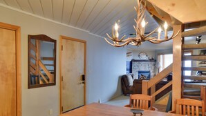 A dining area with a wooden table and chairs, a chandelier, and a staircase leading to another level. - 'eagle's Nest' Crested Butte Townhome w/ Mtn Views (Crested Butte)