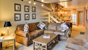 A cozy living room with a brown leather sofa, a wooden coffee table, and a staircase leading to a kitchen. - 'eagle's Nest' Crested Butte Townhome w/ Mtn Views (Crested Butte)