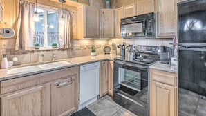 A modern kitchen with wooden cabinets, a stainless steel refrigerator, a microwave, and an oven. - Cabin w/ Mountain Views ~ 2 Mi to Ruidoso Midtown! (Ruidoso)