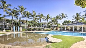 Ein Resort mit großem Schwimmbad, Palmen und einer überdachten Außenanlage.