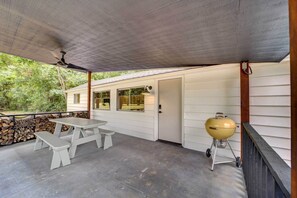 A covered patio with a picnic table and a portable grill. - Scenic Tulsa Getaway w/ Deck + Fire Pit (Tulsa)