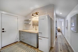 A modern kitchen with white cabinets, a double sink, and a refrigerator. - Scenic Tulsa Getaway w/ Deck + Fire Pit (Tulsa)
